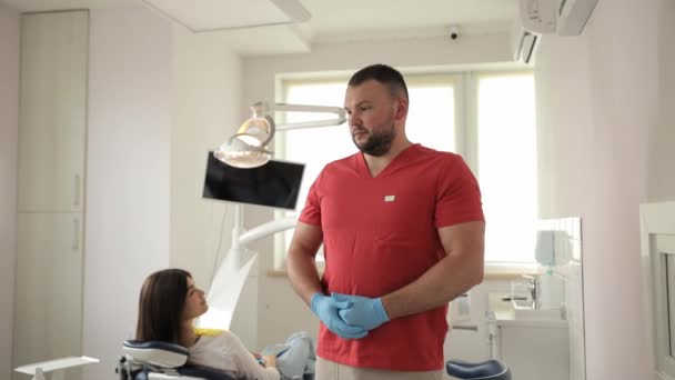赤い医療コートの男性歯科医の肖像画が手を折ってカメラを見ている 歯科治療コンセプト — ストック動画