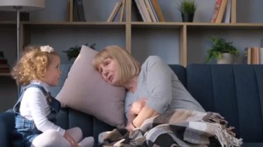 Adorable preschool girl talking with mature retired grandmother, happy grandmother is happy to meet little granddaughter