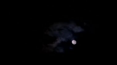 Time lapse of a bright yellow moon at night among dark clouds. Astrology concept.