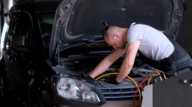 Bir araba tamircisi arabadaki klimayı kontrol eder. Dikey video.