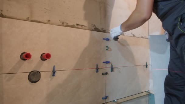 壁にセラミックタイルを敷設 マスターは壁のレベルを測定します バーティカルビデオ — ストック動画