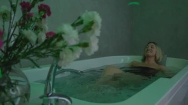 Happy woman lying in bathtub, relaxing hydrotherapy in beauty center. A luxurious woman enjoys a hot tub in a luxury spa