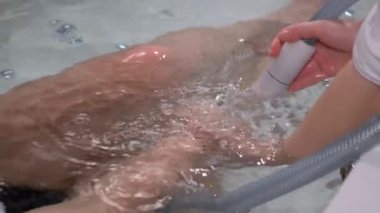 A young cosmetologist gives a beautiful blonde a soothing and rejuvenating water massage. Procedures in the spa salon. Vacation. Caring for your own body.