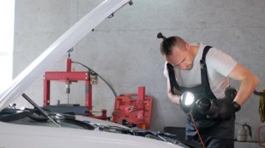 Professional car mechanic repairs car engine, car service.