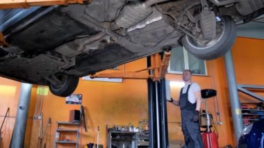 A car mechanic fixing a car from below. The craftsman repairs the chassis of the car. The concept of car repair