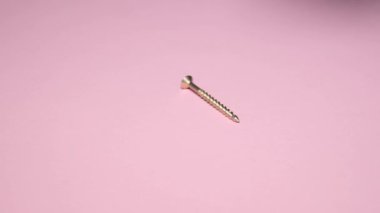 Macro shot of metal bolts on a pink background. Super slow mo.