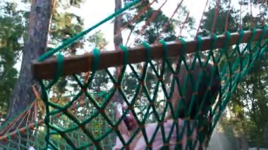 Charming happy woman resting in a hammock and holding a smartphone. A blonde woman lies in a hammock in a pine forest