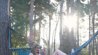A woman with a phone in a hammock. Relaxing in the countryside during the summer holidays.