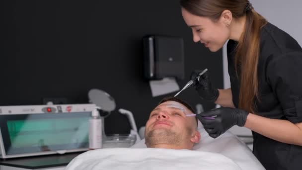一位戴手套的皮肤科医生把面具戴在男人的脸上 在皮肤科诊所为一个男人的脸提供皮肤护理 治疗口罩 — 图库视频影像