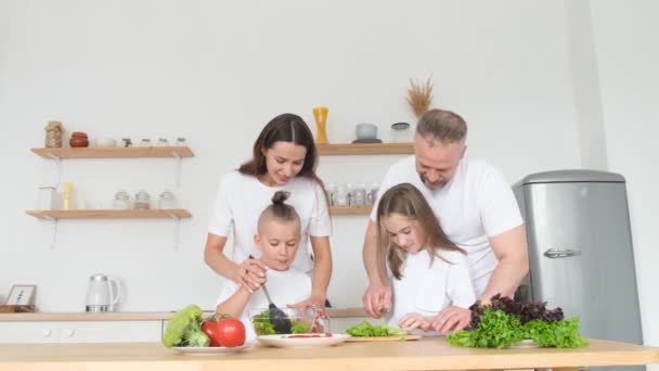 아이들 부엌에서 맛있는 요리를 즐기고 사랑스럽게 미소짓는 부모들이 아이들에게 유기농 — 비디오
