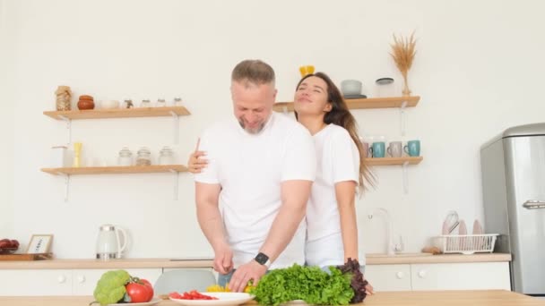 年轻可爱的男人和女人在家里做健康食品的时候笑了 快乐的夫妻喜欢在厨房里一起做饭 垂直录像 — 图库视频影像
