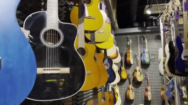 Bir enstrüman dükkanında sergilenen klasik gitarlar. Müzik aletlerinde indirim var. Dikey video