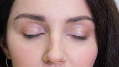 A close-up of a Caucasian brunette opens her eyes wide. Portrait of a beautiful girls face