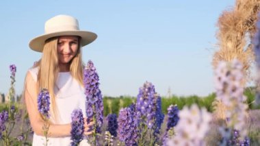 Beyaz şapkalı genç bir kadın lavanta çiçeklerinde mavi gökyüzüne karşı oturur ve güzelliğin tadını çıkarır. Güzellik kavramı ve doğanın keyfi