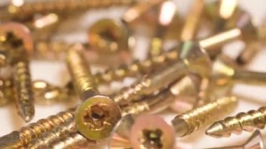 Macro video of falling metal bolts in slow motion. Many metal self-tapping screws for wood.
