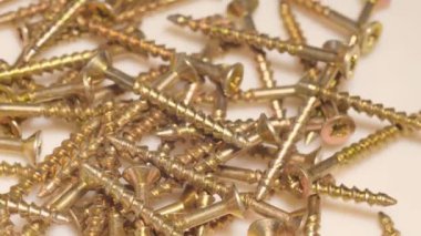 Macro shot of self-tapping screws in a furniture workshop. The use of fasteners when working with wood and plasterboard. Slow motion