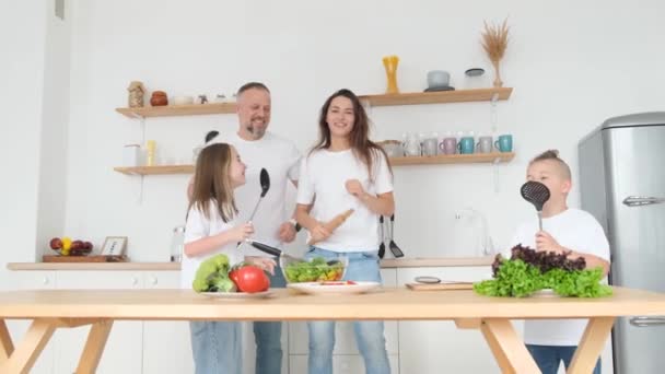 在准备早餐的时候 一家人在厨房里欢快地跳舞 儿子和女儿和父母一起玩 一起做饭 一起唱歌 — 图库视频影像