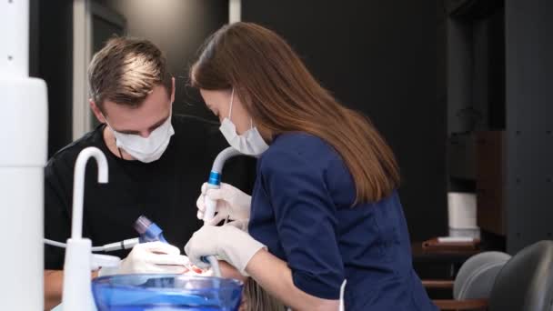 牙医和他的助手在牙科治疗过程中使用现代治疗方法 及时治疗口腔疾病 — 图库视频影像