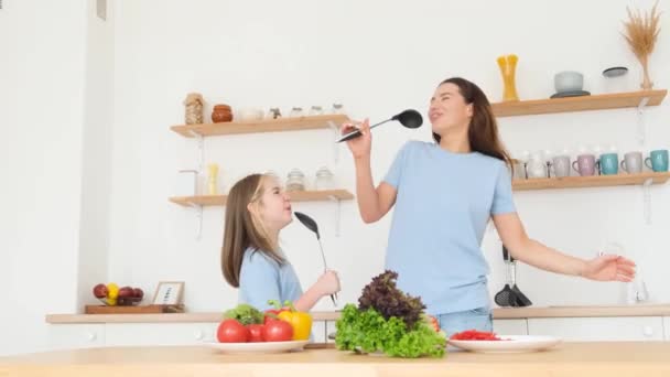 笑顔の母親と娘が自宅の台所でスプーンと歌っている キッチンで料理をする女性と女の子 一緒に幸せな家族 バーティカルビデオ — ストック動画