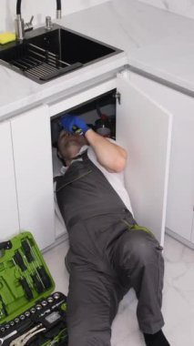 Erkek bir tesisatçı, tesisat reklamı için bulaşık yıkama lavabosu tamir ediyor. Dikey video