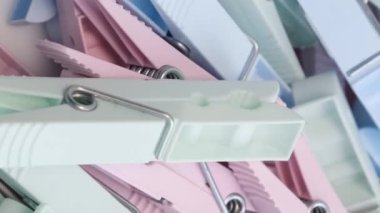 Çamaşırları kuruturken tutmak için çok renkli plastik mandallar. Renkli bir geçmiş. Daire şeklinde döndür. Dikey video