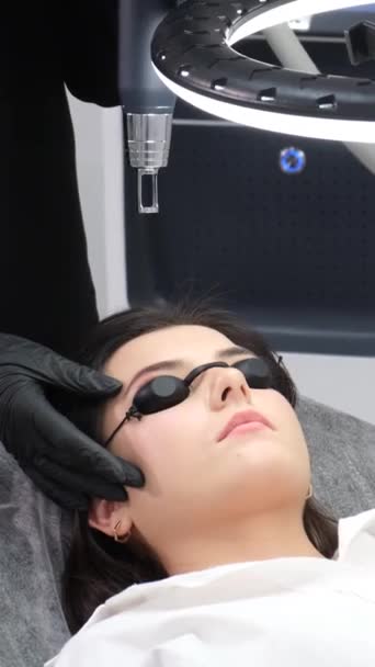 一个戴着防护眼镜在美容院里的小女孩激光面部脱毛工艺采用现代技术 垂直录像 — 图库视频影像