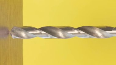 Delik açmak için inşaat aleti. Sarı arka planda sondaj rotasyonu. Marangozluk kavramı ahşaptan yapılmıştır. Dikey video
