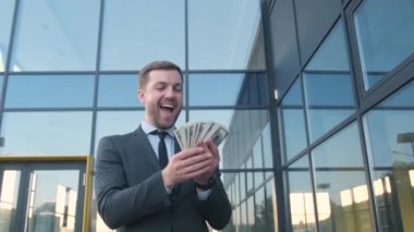 Başarılı bir iş adamı cam iş merkezinin arka planında dolar sayar. Başarı, servet, kariyer gelişimi, lotoyu kazanmak.