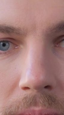 Close-up of the face of a European man looking into the camera and slowly closing his eyes. Portrait of a handsome young man. Vertical video