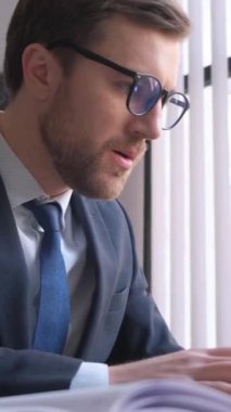 Adult caucasian angry businessman tired in office at desk, stressed with paperwork, deadline, upset, work problems, hard work week. Vertical video