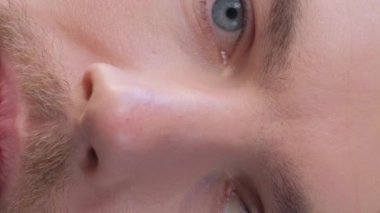 Close-up of the face of a European man looking into the camera and slowly closing his eyes. Portrait of a handsome young man. Vertical video