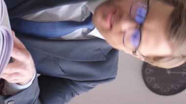 A tired office worker, he has a lot of work that he does not have time to do. Angry business worker. Vertical video