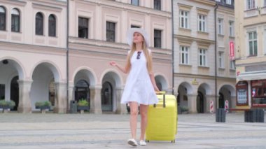 Güzel genç bir bayan şehre bakıyor. Turist bir kız elinde bavulla turist konutları arayarak yürüyor..