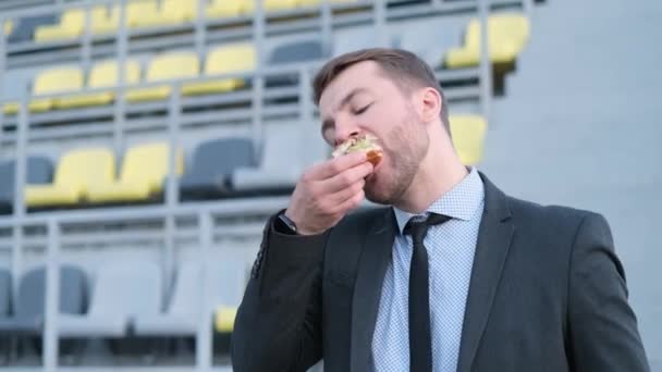Mladý Americký Kancelářský Pracovník Obědvá Venku Sendvič Zatímco Sedí Lavičce — Stock video