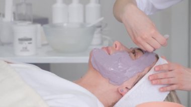Close-up of a womans face during the application of a moisturizing and rejuvenating mask by a beautician. Relaxed woman in beauty salon during facial treatments