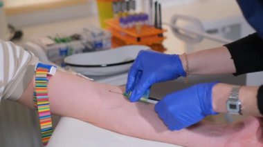 A nurse in gloves takes blood from a patients vein, making a puncture with a needle. Blood sampling for laboratory tests. Diagnosis of the patients blood