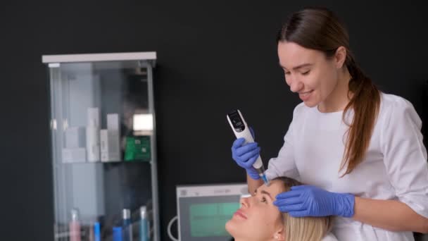按摩治疗师为病人进行真空滚筒按摩 一个女人在美容院里修正了脸的形状 脸的构造 一位年轻女子接受了电动面部按摩 — 图库视频影像
