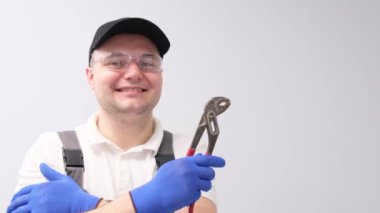 Anahtarı olan bir tesisatçı portresi, gülümsüyor ve baş parmağını kaldırıyor. Tesisat hizmetleri
