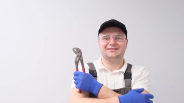 İngiliz anahtarı olan profesyonel tesisatçı, gülümsüyor ve beyaz arka planda stüdyoda poz veriyor..