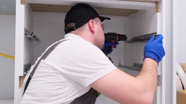Een Mannelijke Arbeider Installeert Meubels Een Nieuw Huis Keukenaccessoires — Stockvideo