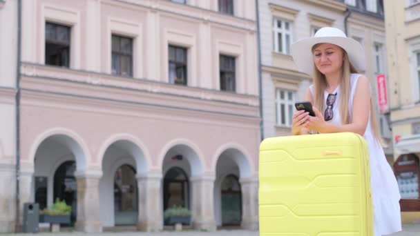 Μια Νεαρή Γυναίκα Λευκό Καπέλο Και Κίτρινη Βαλίτσα Περιμένει Λεωφορείο — Αρχείο Βίντεο