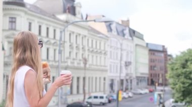 Gezgin kız kahve içip Avrupa mimarisine hayran olan eski şehre bakıyor. Yaz tatilini rahatlatmak için iç. Hafta sonu için rahatlatıcı bir gezi..