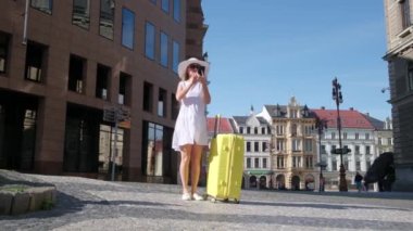 Çek Cumhuriyeti Prag sokaklarında sarı bavullu bir kadın gezgin yürüyor..