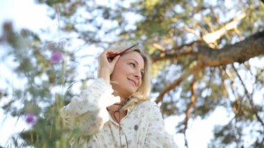 Ormanda dinlenen gülümseyen bir kadınla mutluluk ve özgürlük kavramı. Doğanın tadını çıkaran ve kollarını enerjiyle açan bir kadın..