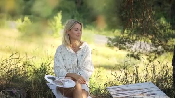 一个女人在森林里的帆布上画画 快乐的艺术家在户外 镜框里明亮的阳光 — 图库视频影像