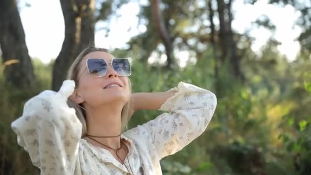 戴着太阳镜的金发碧眼的人在户外放松 秋天森林里的女人镜框里明亮的阳光 — 图库视频影像