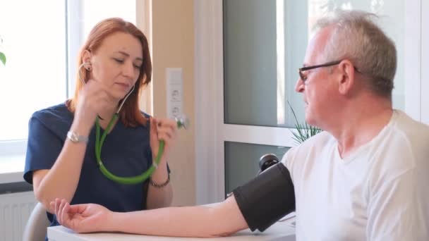 Kvinnlig Kardiolog Som Mäter Blodtrycket Hos Äldre Patient Läkarmottagningen Äldre — Stockvideo