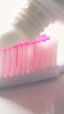 Diş fırçasına diş macunu sürerken çekilmiş makro bir video. Diş bakımı konsepti. Diş macununun reklamı.