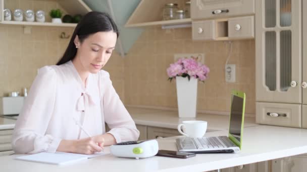 Genç Bir Kadın Mutfakta Dizüstü Bilgisayarla Masada Oturuyor Bilgiler Yazılıyor — Stok video