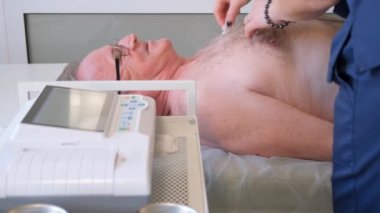 Profesyonel bir doktor yaşlı bir adam için kalp kardiyogramı yapar. Klinikte tıbbi muayene..